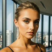 Woman in a black dress standing in front of large windows with a cityscape view.